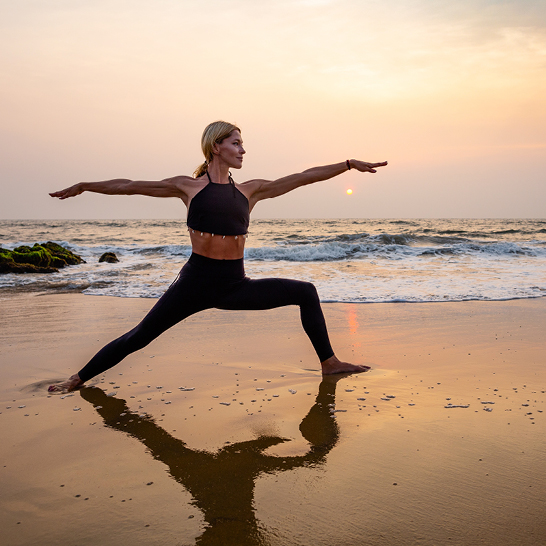 Une femme pratique le yoga sur la plage aux Seychelles, avec un magnifique coucher de soleil en arrière-plan.