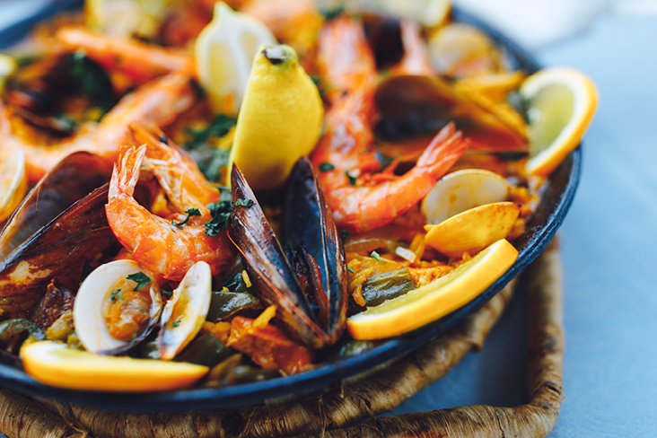 Ein Teller mit Meeresfrüchten und Gemüse, garniert mit einer Zitronenscheibe, typisch für die spanische Küche.
