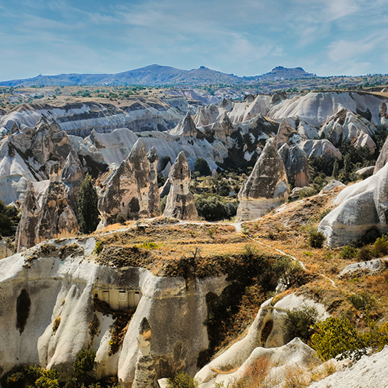 Blick auf eine Bergkette in der Türkei mit einem vorbeifahrenden Zug im Vordergrund.