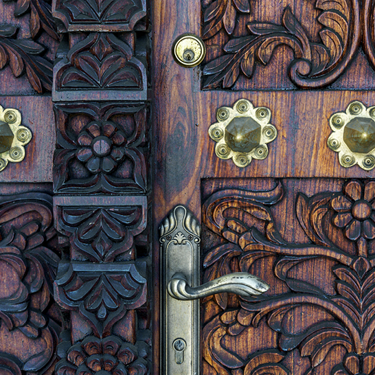 Eine kunstvoll verzierte Tür mit detaillierten Schnitzereien und glänzenden Messingknöpfen aus Tansania.