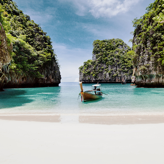 Un bateau repose sur la plage près d'une côte rocheuse à Phuket et Koh Phi Phi.