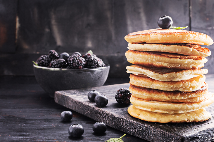 Ein Stapel Pfannkuchen, garniert mit Beeren und Minzblättern.