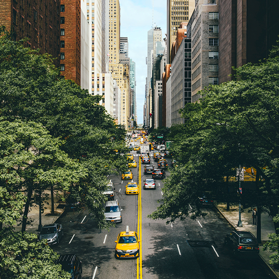 Eine Stadtstrasse in NYC mit einem gelben Taxi, das auf der Strasse fährt.