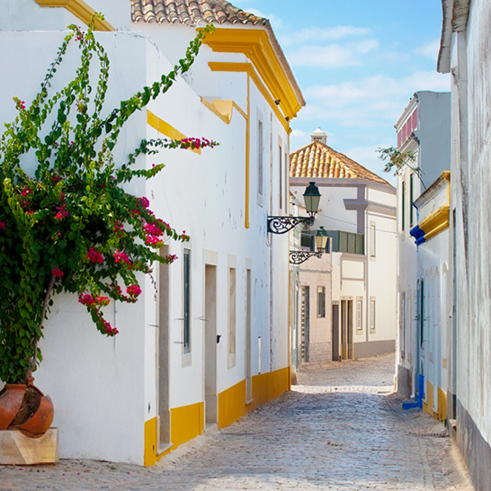 Enge Strasse in Faro mit gelben und weissen Gebäuden, die eine charmante Atmosphäre schaffen.