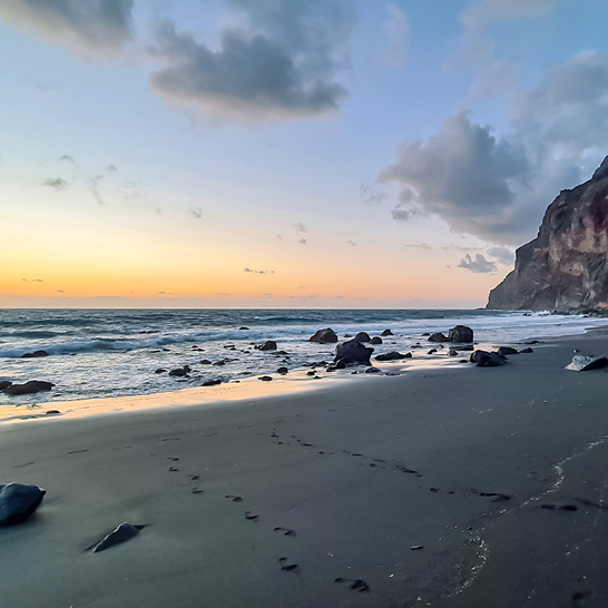 Ein Strand mit Felsen und Wasser bei Sonnenuntergang auf La Gomera, Kanaren.