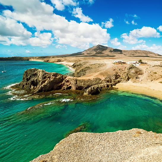 Strand mit klarem Wasser und felsiger Küste auf Lanzarote, Kanaren.