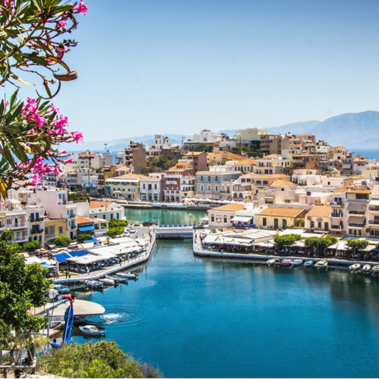 Blick auf den Hafen von Agios Nikolaos mit einigen Booten und Gebäuden im Hintergrund.